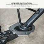 Close-up of a black and silver metal bicycle stand base with a textured black grip pad, shown with text at the top reading 'EXTENDED FOOTPRINT AREA' and a small explanatory note about increased footprint area.