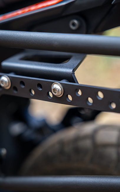 Adjustable slots Close-up of a motorcycle's black metal frame with bolts, blurred background