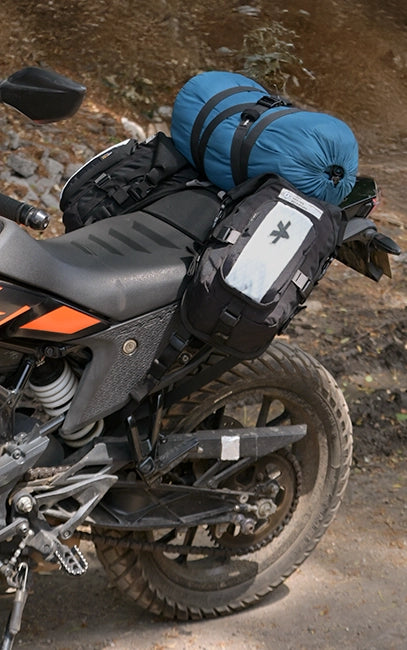 Bridge MOLLE Panel Motorcycle with a blue bag on a dirt path
