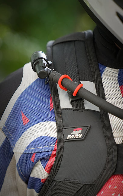 Fidlock Tube Keeper Close-up of a black Darn Tough motorcycle chest protector with an orange-red buckle, attached to a black handlebar bar, worn by a rider in blue, white, and red patterned riding gear.