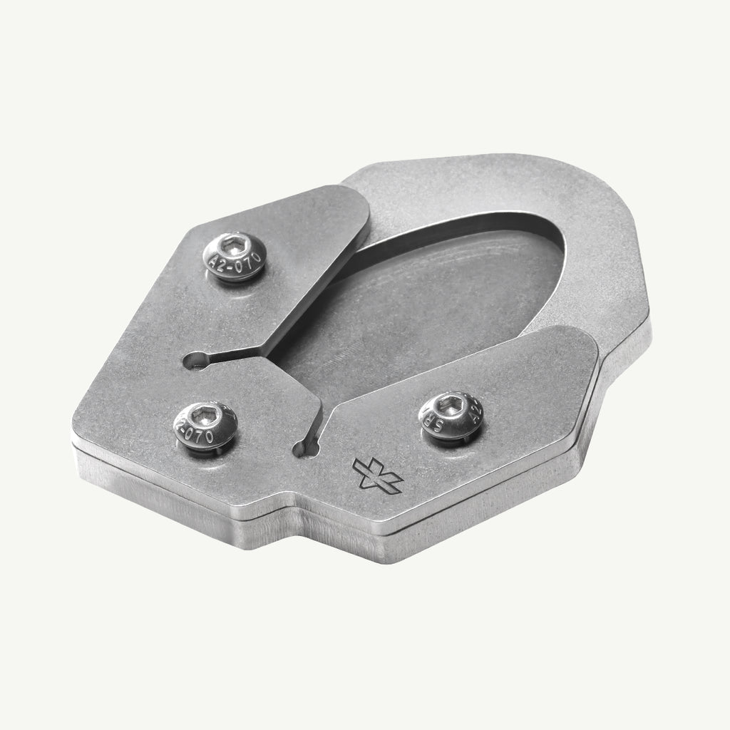 A metallic silver metal shoe clip with three adjustable screws and a small engraved logo, shown on a light off-white background.