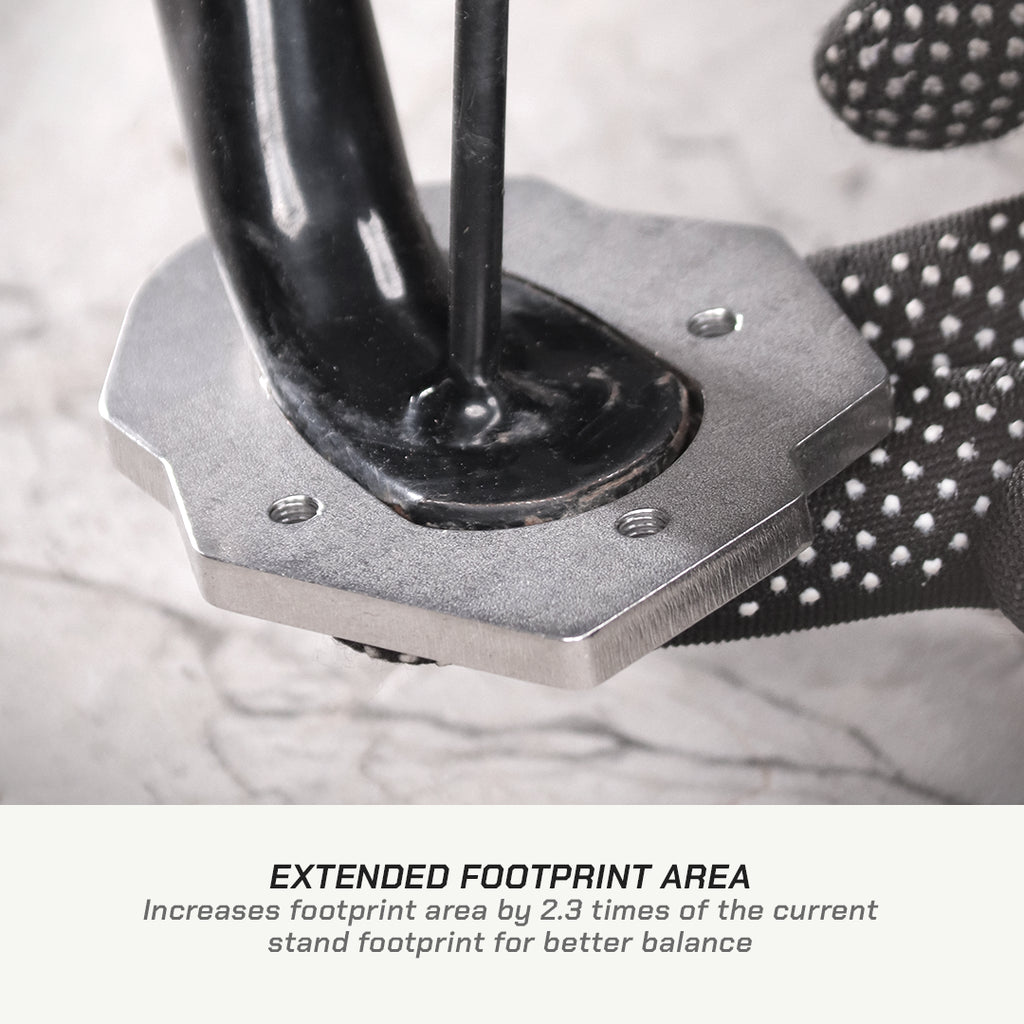 Close-up of a black and silver metal foot stand with a textured black grip, shown on a light stone surface with text below reading 'EXTENDED FOOTPRINT AREA'.
