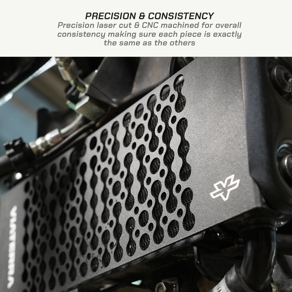 color_black Close-up of a black perforated metal engine cover or shroud with a white stylized logo, shown with a text banner at the top reading 'PRECISION & CONSISTENCY' and a small amount of white space above.