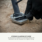 color_common Person using a tool to clamp a shoe onto a metal stand on a dirt surface.