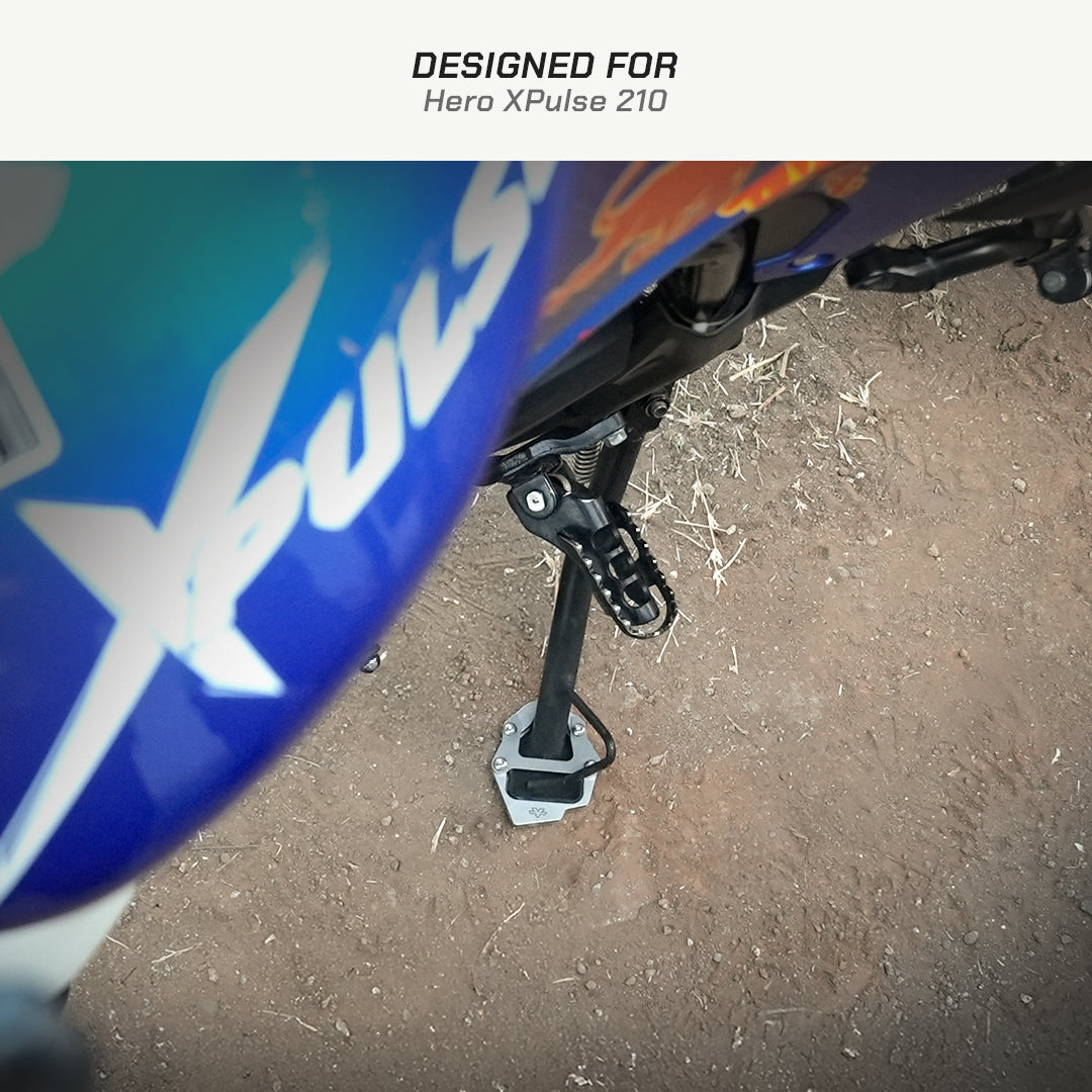 color_common Close-up of a motorcycle foot peg with 'Xpulse' branding on a dirt surface, labeled 'Designed for Hero XPulse 210'.
