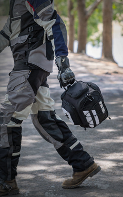 Integrated Grab Handle Person in motorcycle gear holding a helmet with a scenic background