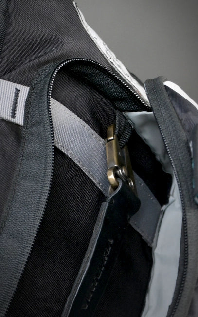 Internal Utility Loop Close-up of a black and gray backpack with a zipper and carabiner.