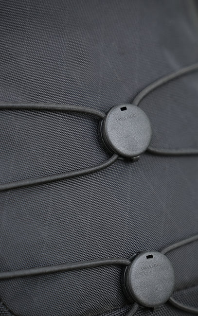 Lightweight X-Pac Construction Close-up of a dark gray textured fabric surface with two circular gray hardware pieces connected by thin cords.