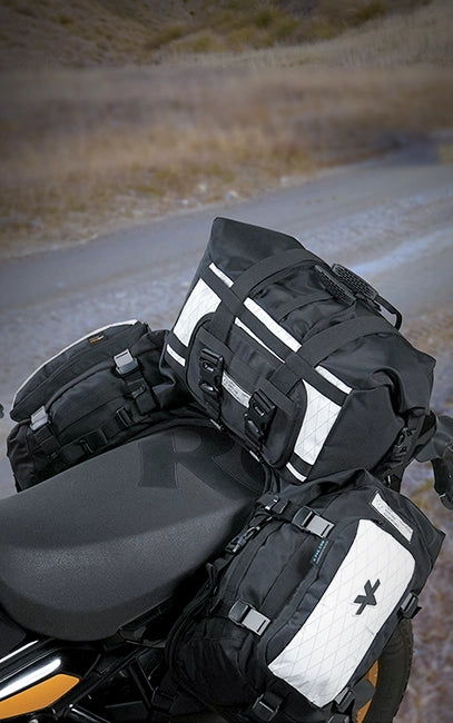 Load Expansion Holster Motorcycle with black travel bags attached to the seat on a road.