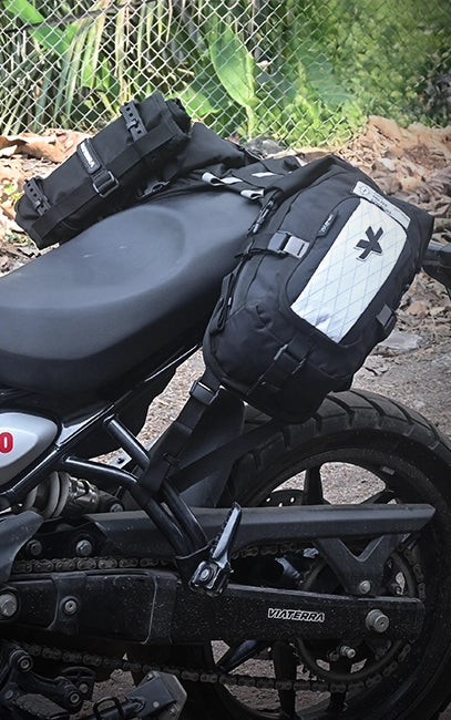 MOLLE Utility Loops Motorcycle with black saddlebags attached to the back, parked outdoors.