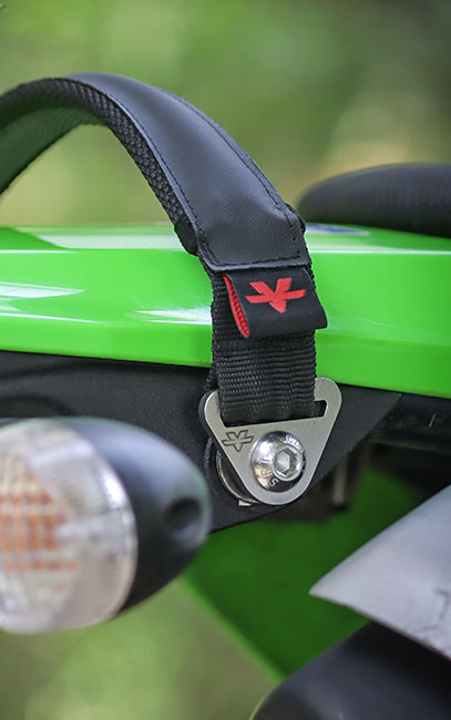 Premium build and finish Close-up of a black motorcycle handlebar strap with a red embroidered logo, secured to a bright green motorcycle body panel.
