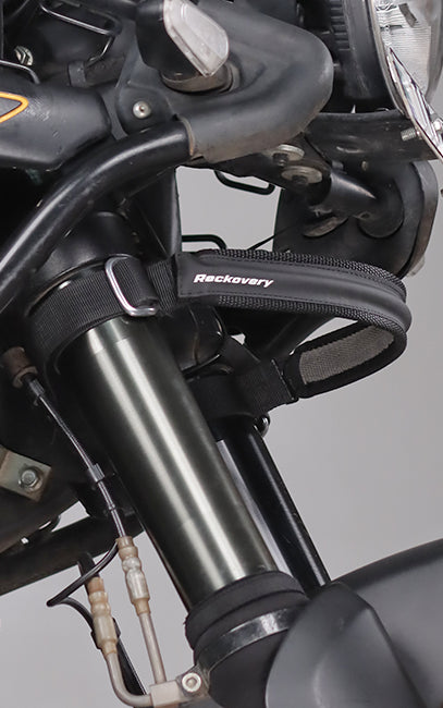 Premium build and finish A close-up of a black motorcycle front fork secured with a black recovery strap featuring the white 'Recovery' brand logo.