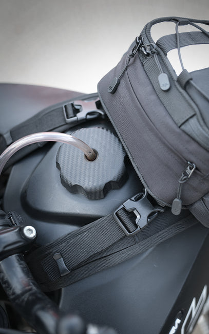 Quick-Release Buckles Gray bag attached to a motorcycle with a blurred background