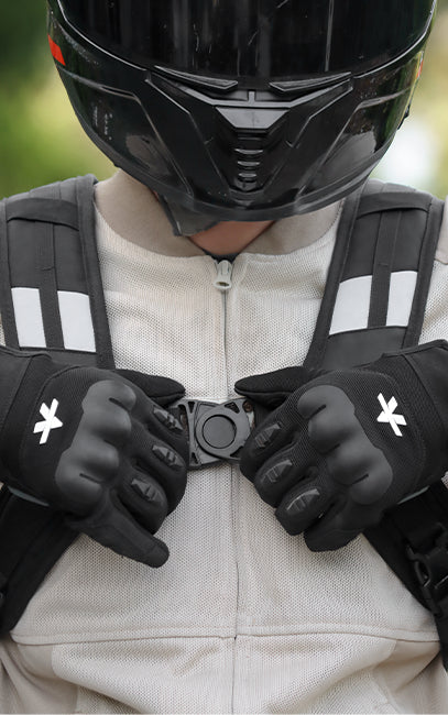 Swivel Lock Sternum Closure Close-up of a person wearing a black full-face motorcycle helmet, black gloves with white logo details, and a light beige zip-up riding jacket with black shoulder armor.