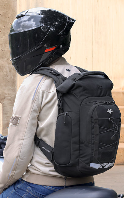Designed to Reduce Fatigue A black motorcycle backpack with reflective details and bungee cord accents, shown on a rider wearing a black helmet and beige jacket.