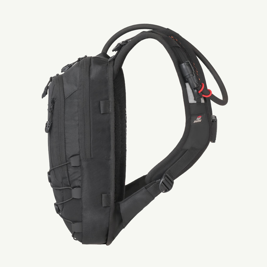 A black hydration backpack shown from the side profile against a light off-white background. The backpack features a black shoulder strap, a black hydration tube with red accents, and multiple zippered compartments.