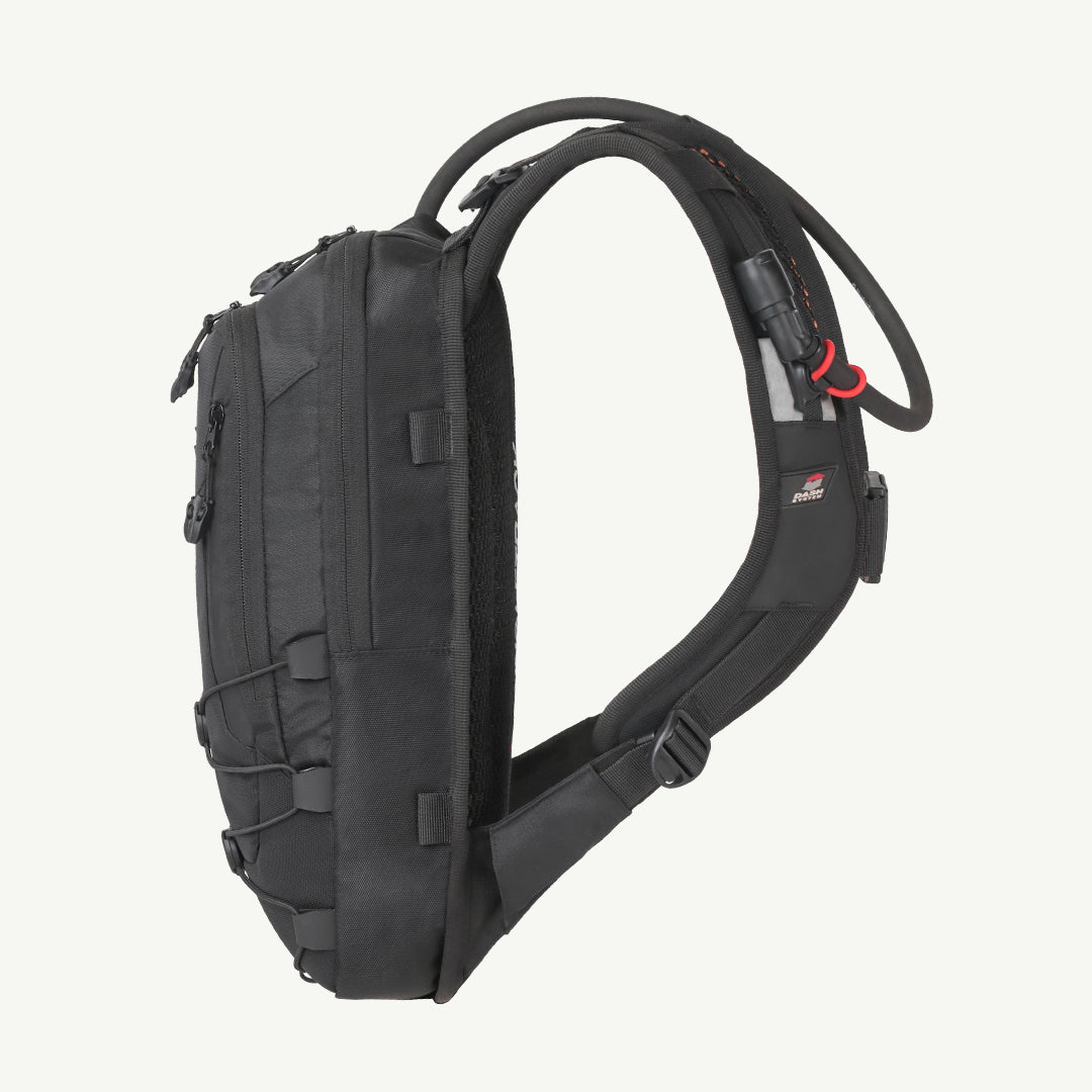 A black hydration backpack shown from the side profile against a light off-white background. The backpack features a black shoulder strap, a black hydration tube with red accents, and multiple zippered compartments.
