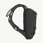 A black technical running backpack shown from a side profile view against a solid off-white background. The backpack features a padded shoulder strap, compression buckles, and multiple zippered compartments.
