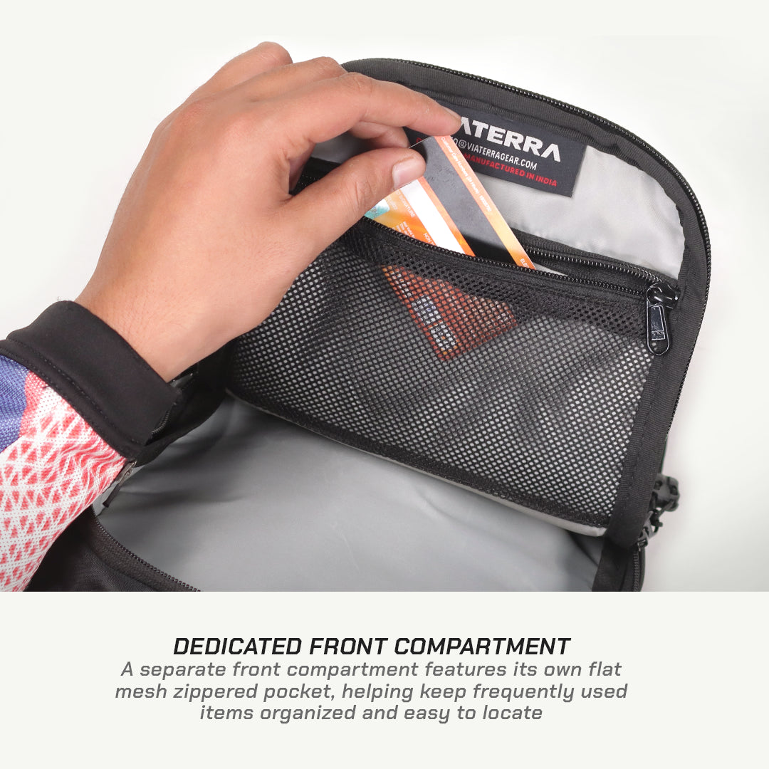 Close-up of a hand placing an item into a black mesh front compartment pocket of a gray and black backpack, with a brand label reading NITERRA visible inside. Text below explains the dedicated front compartment.