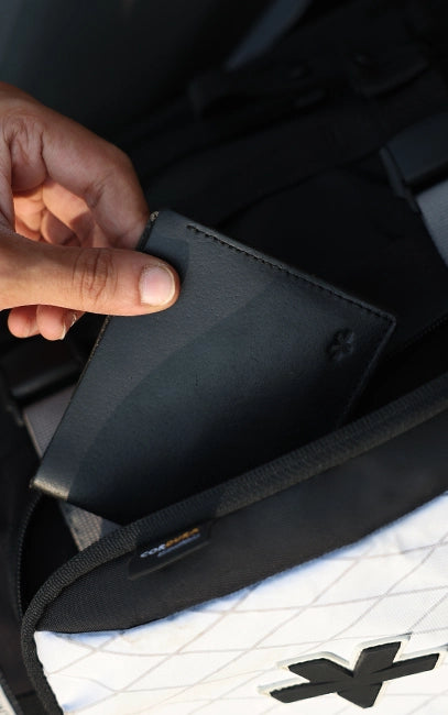 X-Pac Quick Access Pocket Person opening a black suitcase with a brand logo on a white background